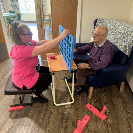 Resident and carer enjoying playing a game